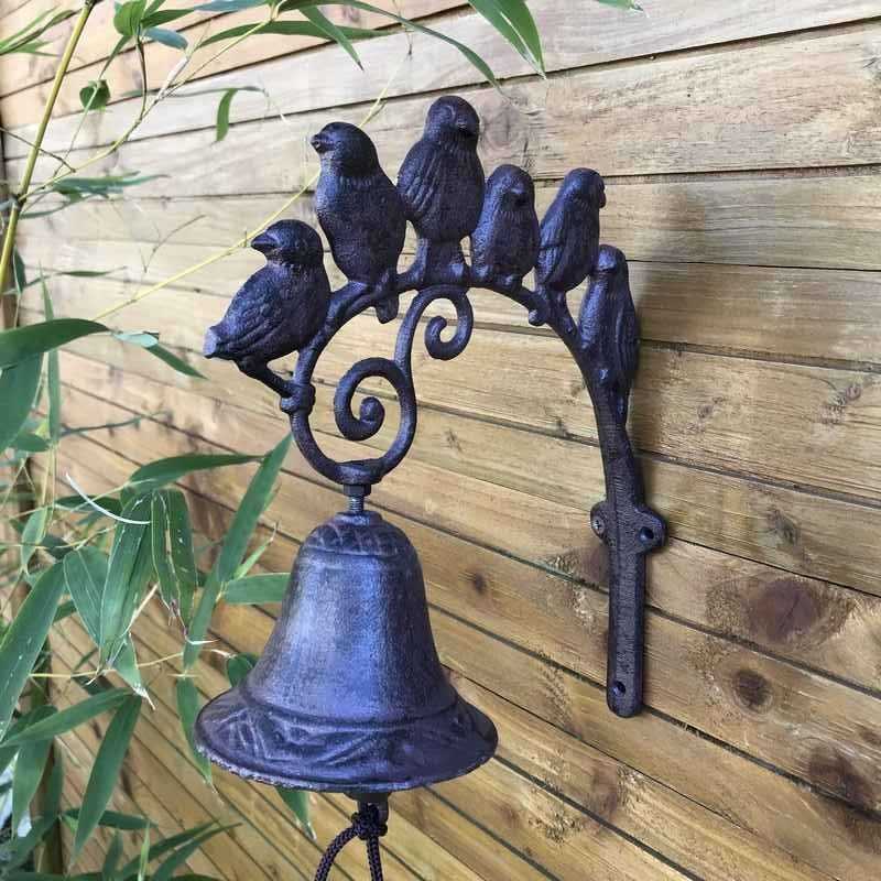Gietijzeren deurbel voor tuinpoort met vogelmotief sfeervol gepresenteerd
