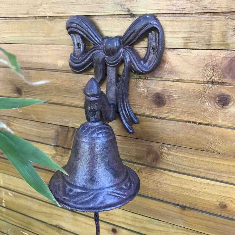 Gietijzeren deurbel voor tuinpoort met strikmotief, sfeervol gepresenteerd