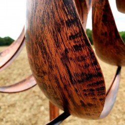 Decoratieve tuinwindmolen van koperkleurig ijzer, gezien vanaf het blad