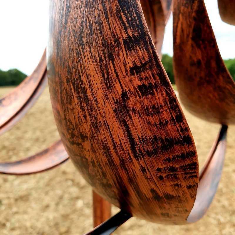 Decoratieve tuinwindmolen van koperkleurig ijzer, gezien vanaf het blad