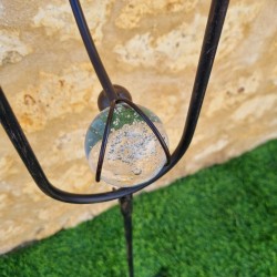 Tuinmobiel van smeedijzer met kraaienmotief en pin, uitgebalanceerde steun met zicht op het contragewicht van belucht glas