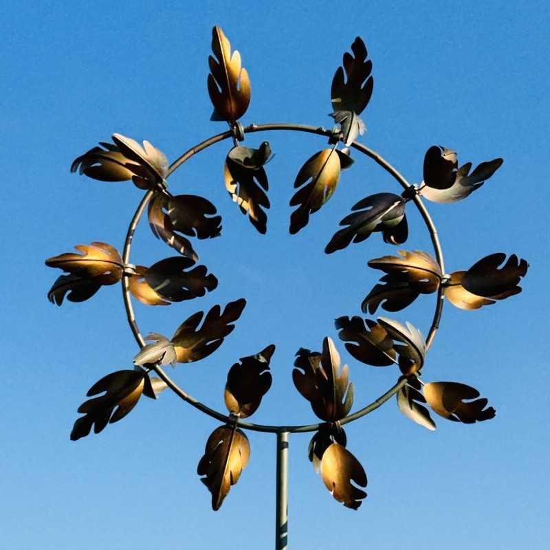 Decoratieve tuinwindmolen van gepatineerd metaal – elegantie en beweging voor uw buitenruimte gezien tegen een blauwe lucht