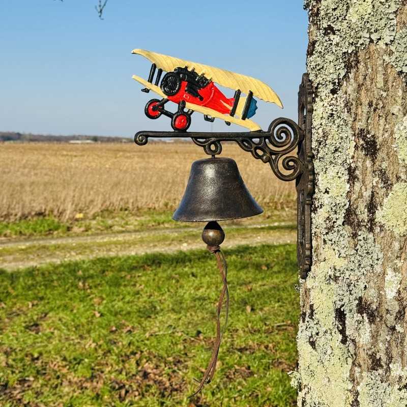 Gietijzeren wandbel gemonteerd op een muur met een kleurrijk tweedekker vliegtuig