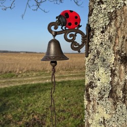 Gietijzeren wandbel met lieveheersbeestje, geplaatst in een landelijke setting
