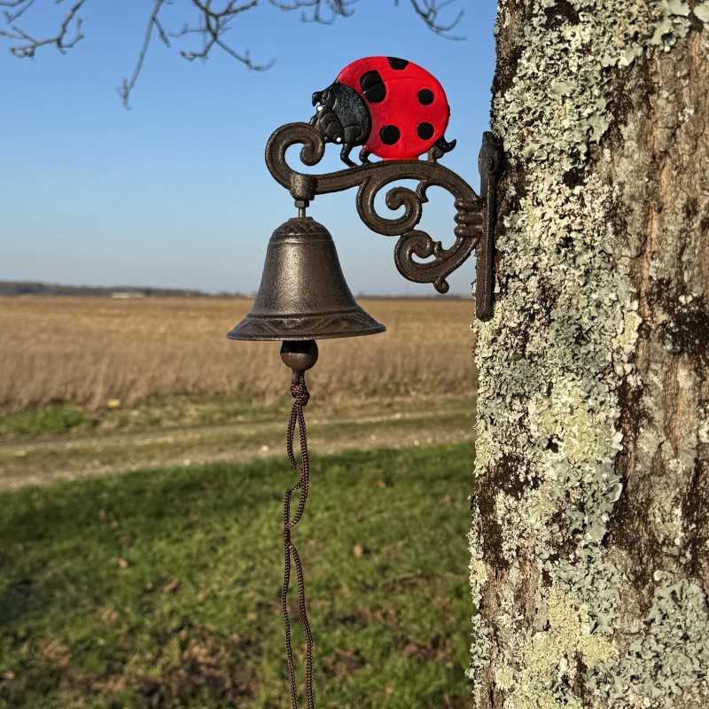 Gietijzeren wandbel met lieveheersbeestje, geplaatst in een landelijke setting